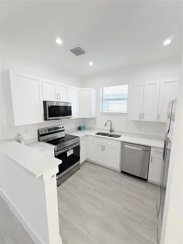 a kitchen with a sink a stove a microwave a counter top space and cabinets
