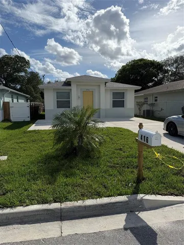 front view of house with a yard and potted plants