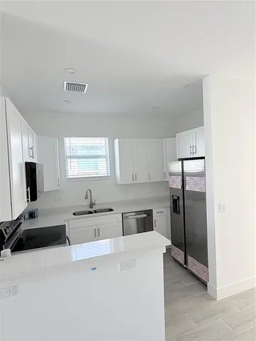 a kitchen with stainless steel appliances a refrigerator sink and white cabinets