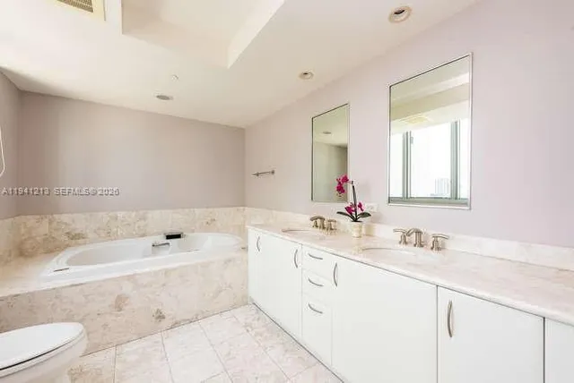 a bathroom with a tub a sink and mirror