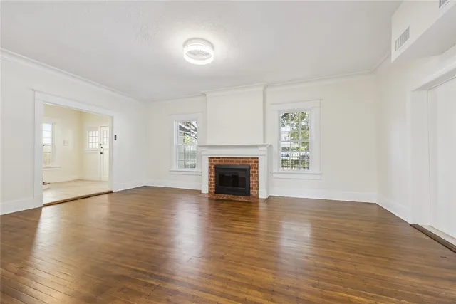 an empty room with wooden floor fireplace and windows