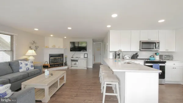 a living room with stainless steel appliances furniture a fireplace a flat screen tv and a window