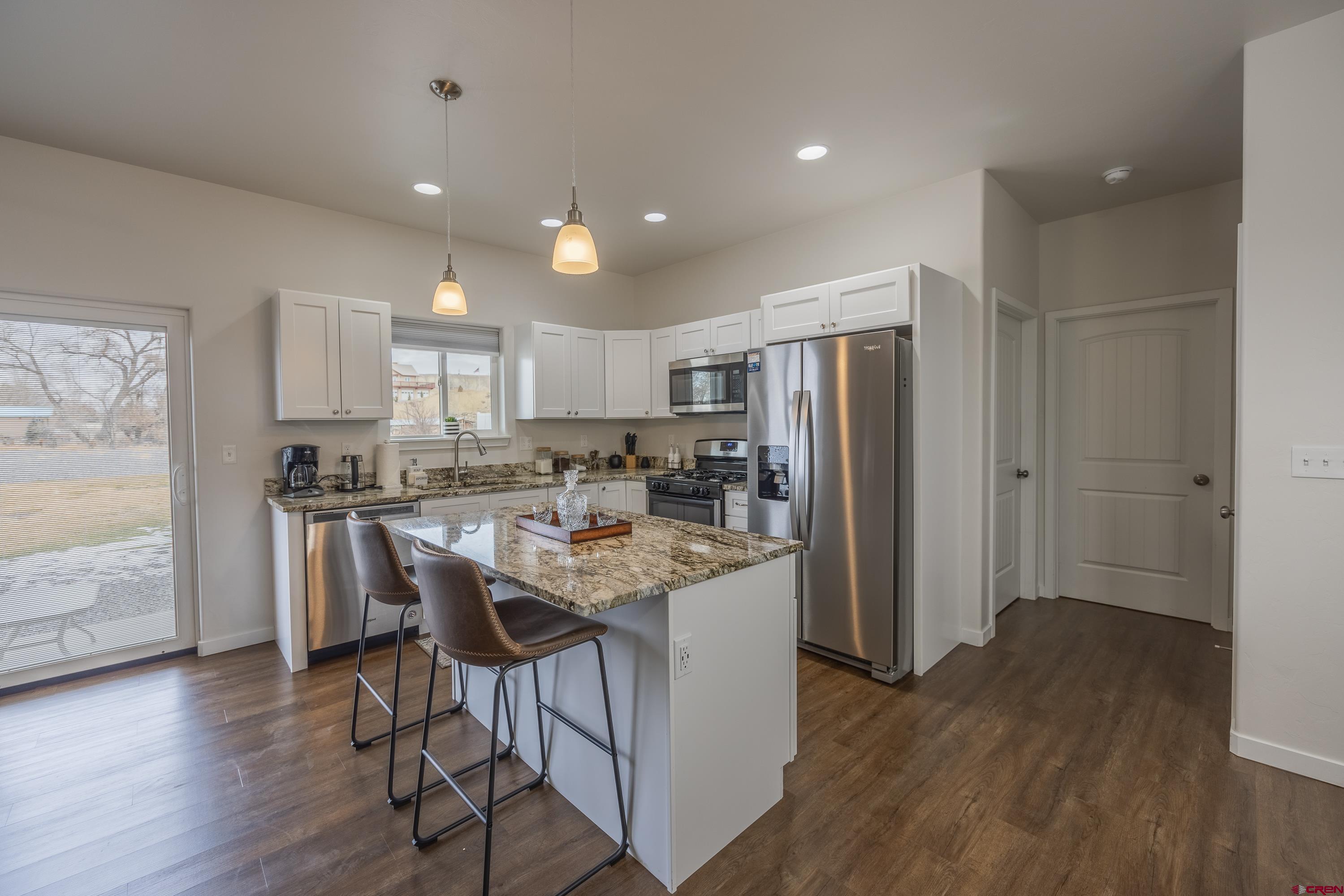 1725 Moonlight Drive Montrose, CO 81401 - Photo 13 of 35 a kitchen with stainless steel appliances granite countertop a refrigerator a stove a sink and a dining table with wooden floor