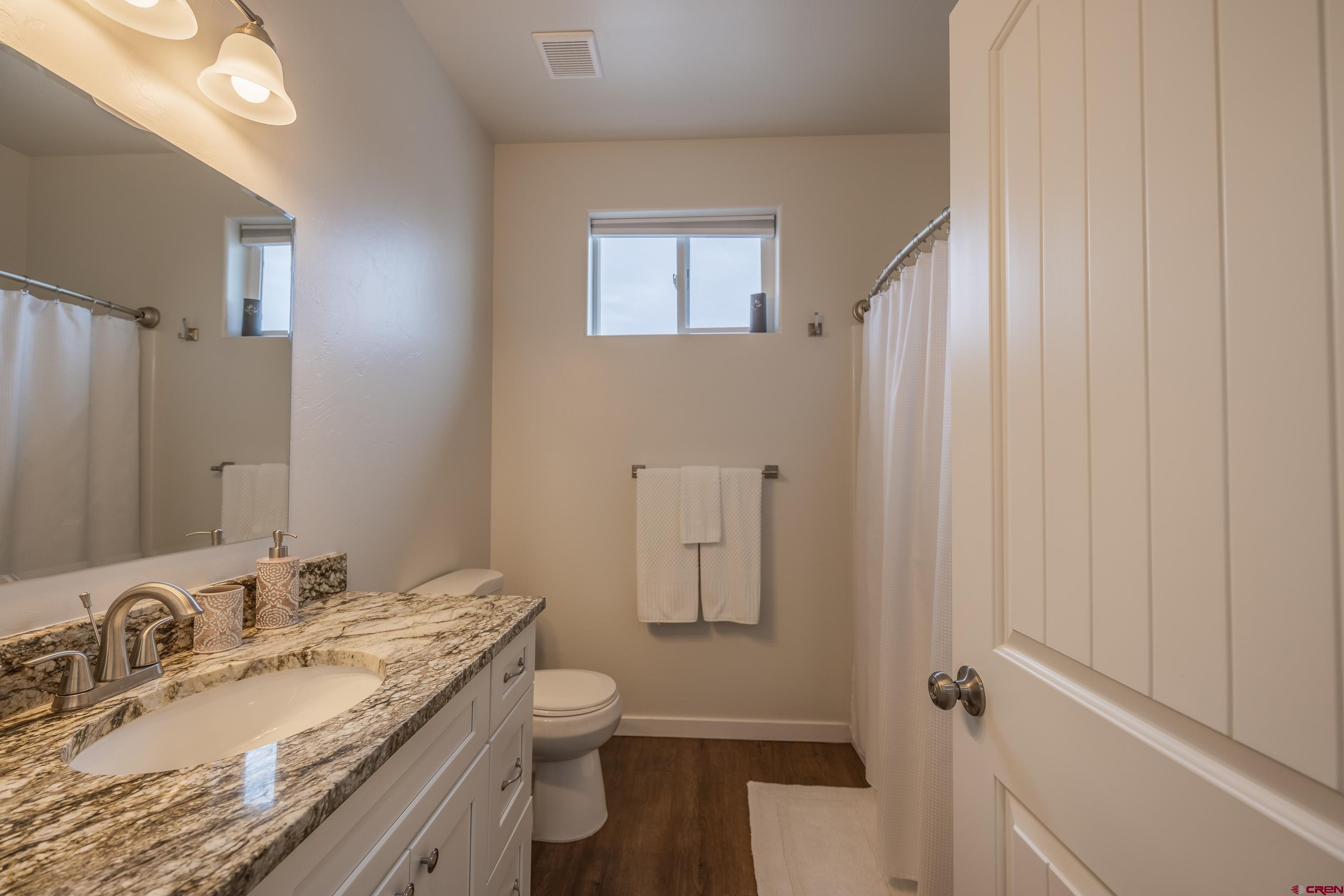 1725 Moonlight Drive Montrose, CO 81401 - Photo 27 of 35 a bathroom with a granite countertop sink toilet and shower curtains