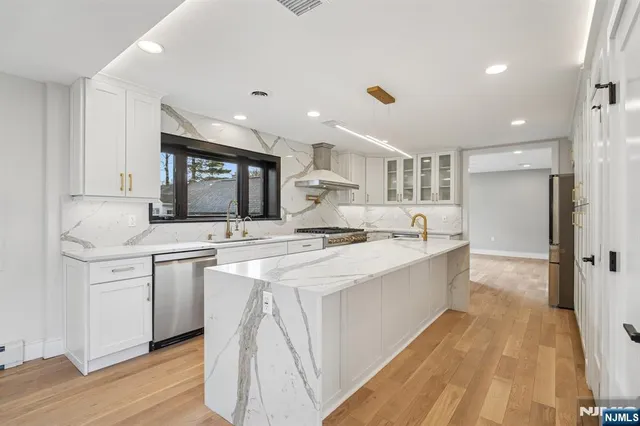 a large kitchen with kitchen island a sink a center island stainless steel appliances and a cabinets