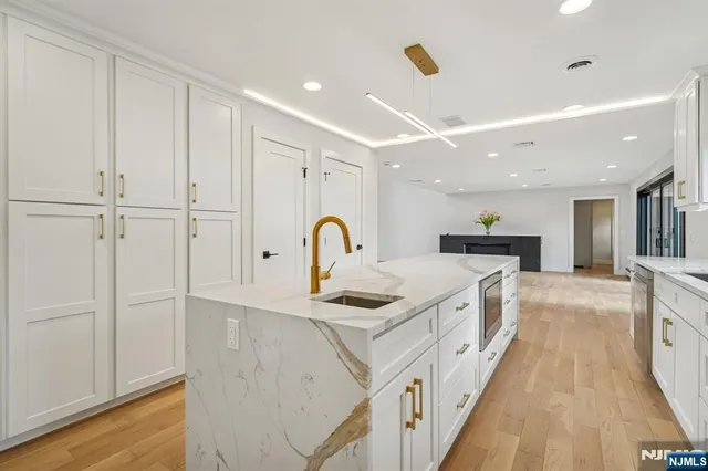 a view of a kitchen with kitchen island a sink wooden floor and living room view