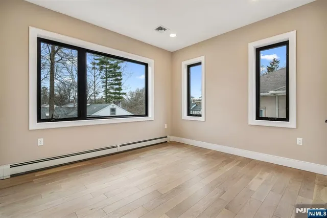 a view of an empty room with a window and wooden floor
