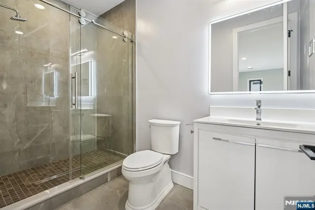 a bathroom with a shower sink mirror and toilet