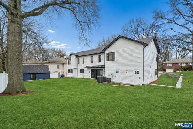 a house that is sitting in the grass with large trees