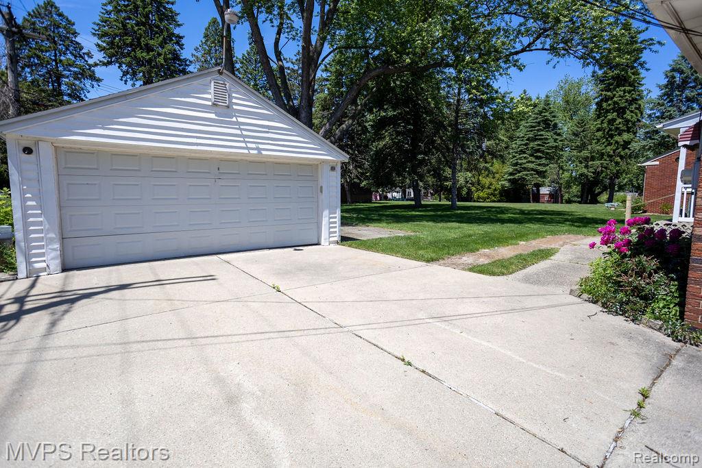 33033 Edgegrove Road Fraser, MI 48026 - Photo 3 of 20 Detached garage with white vinyl siding, a white panel garage door, and a concrete driveway