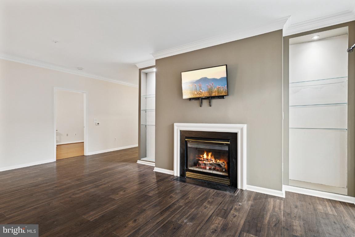 20903 Cedarpost Square, Unit 101 Ashburn, VA 20147 - Photo 2 of 26 a view of an empty room with wooden floor a fireplace and a window