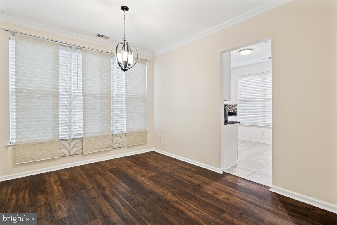 20903 Cedarpost Square, Unit 101 Ashburn, VA 20147 - Photo 6 of 26 an empty room with wooden floor cabinet and windows
