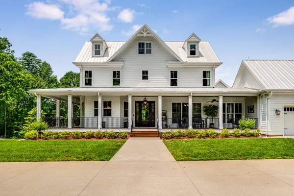 a view of a white house with a small yard and plants
