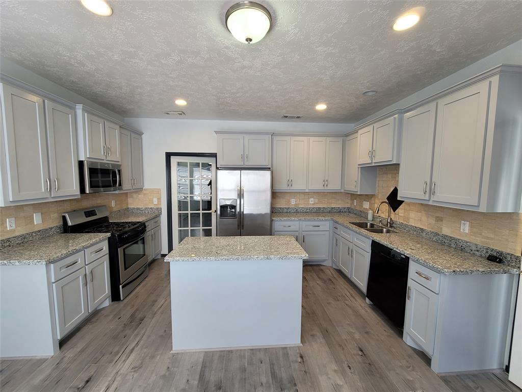 a large kitchen with stainless steel appliances granite countertop a stove a sink dishwasher and a refrigerator