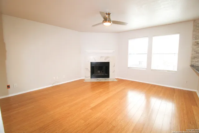 an empty room with windows and fireplace