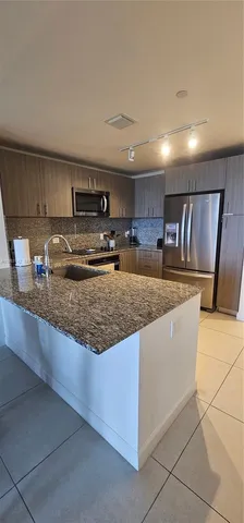 a kitchen with stainless steel appliances granite countertop a sink a stove and a refrigerator