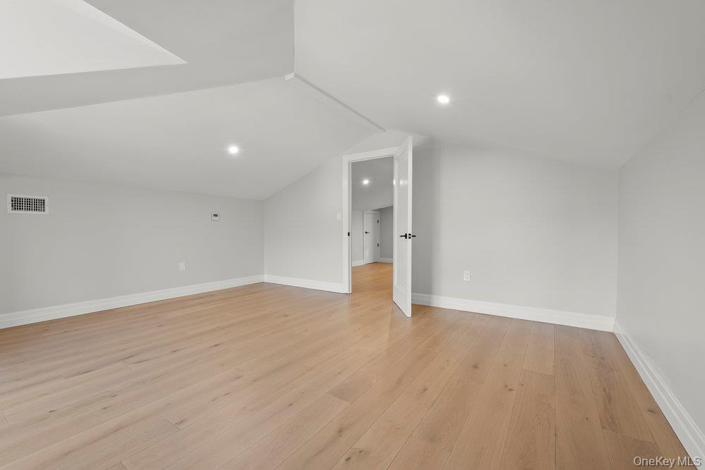 176-12 Kildare Road Queens, NY 11432 - Photo 32 of 34 Additional living space featuring light wood-type flooring, vaulted ceiling, and recessed lighting