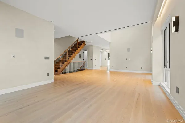 a view of an empty room with wooden floor and stairs
