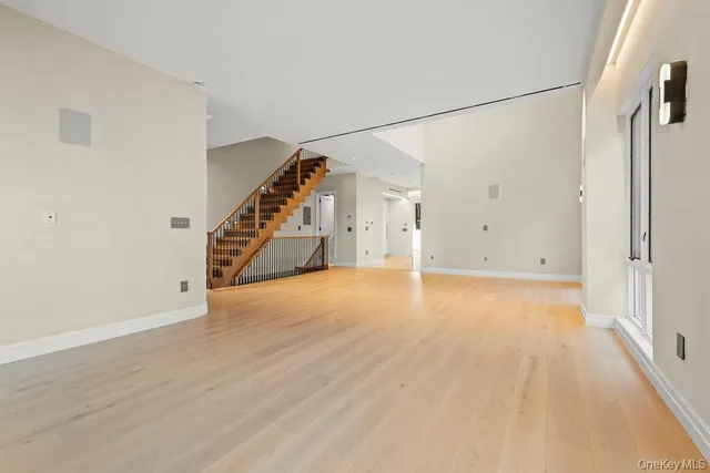 a view of an empty room with wooden floor and stairs