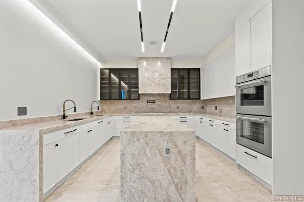 a large white kitchen with stainless steel appliances granite countertop a sink dishwasher stove and oven