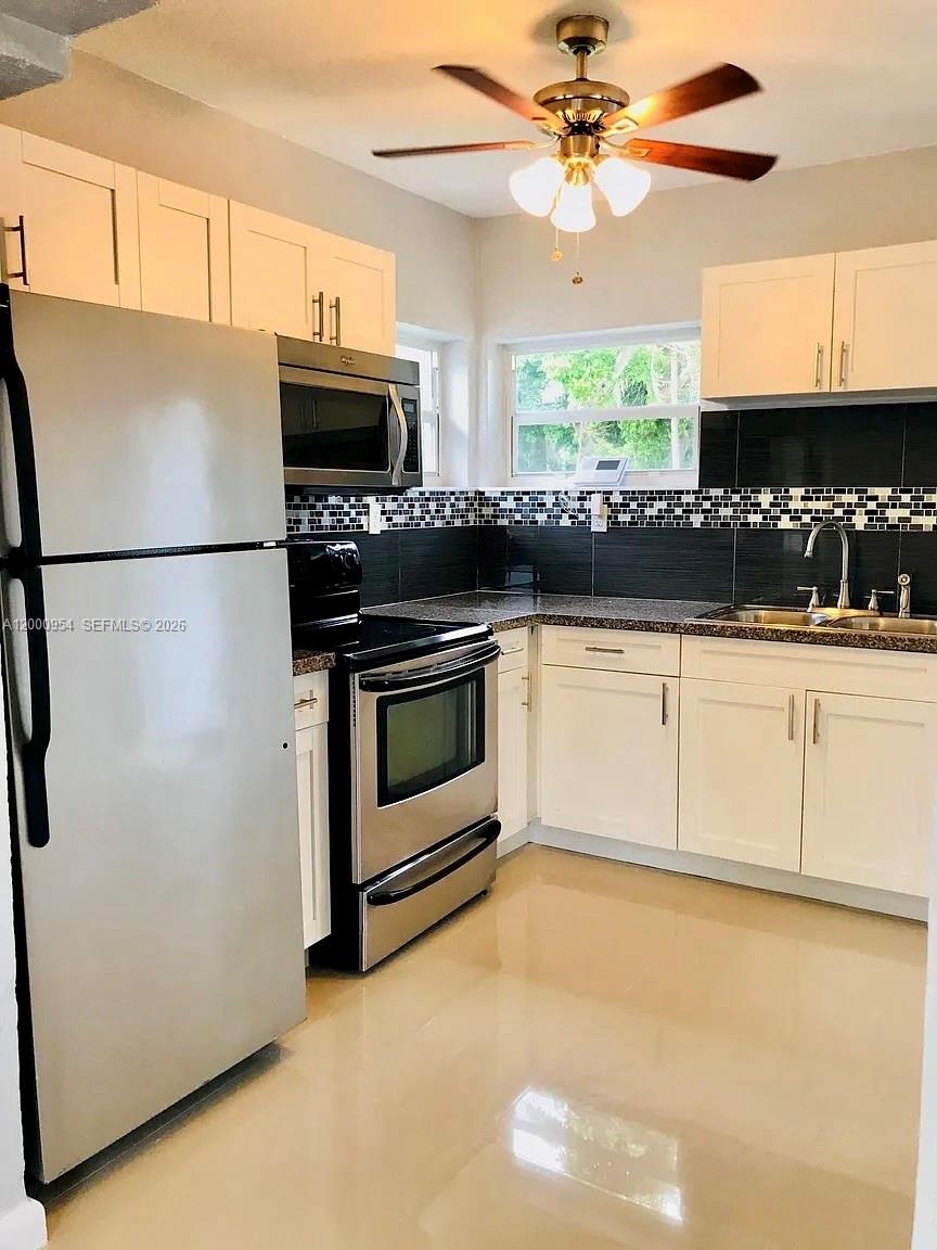 535 Northeast 68th Street, Unit UPSTAIRS Miami, FL 33138 - Photo 4 of 14 a kitchen with granite countertop a refrigerator a stove a microwave and cabinets