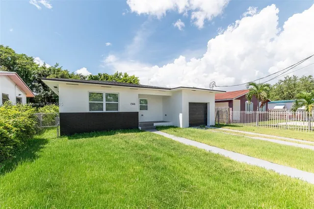 a front view of house with yard and trees in the background