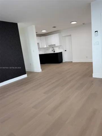 a view of kitchen and empty room with wooden floor