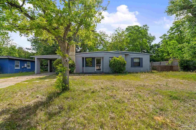 a view of a house with a yard and large tree