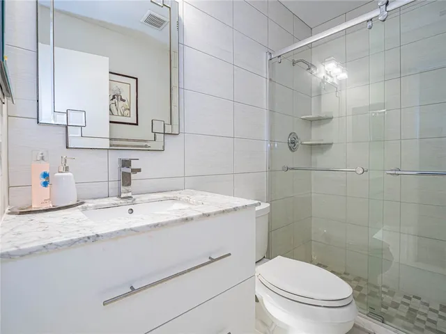 a bathroom with a granite countertop toilet sink mirror and shower
