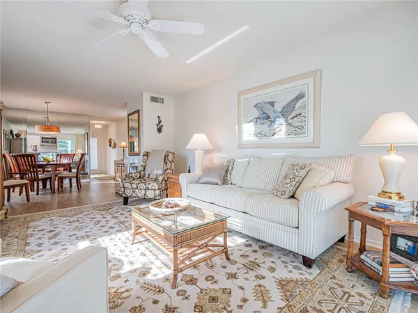 a living room with furniture and a dining table with wooden floor