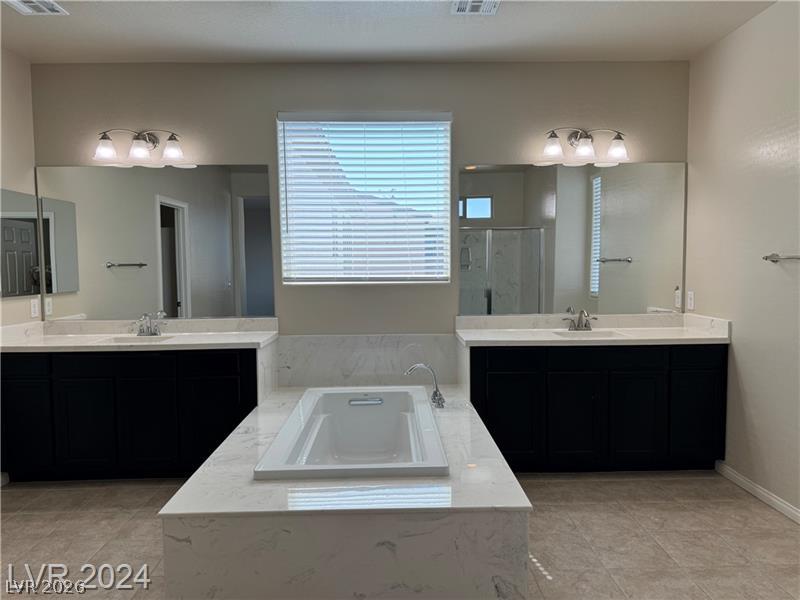9056 Tony Ridge Avenue Las Vegas, NV 89148 - Photo 17 of 32 Indulge in a tranquil retreat featuring dual vanities, a deep soaking tub, and ample counter space.
