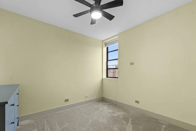 an empty room with a ceiling fan and a window