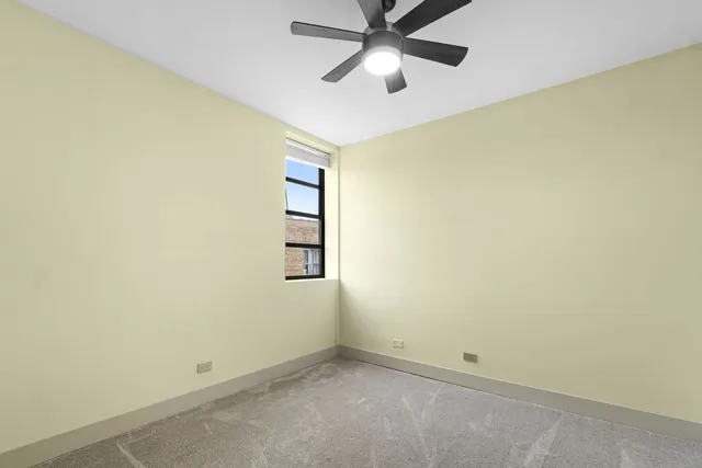 an empty room with a window and a fan