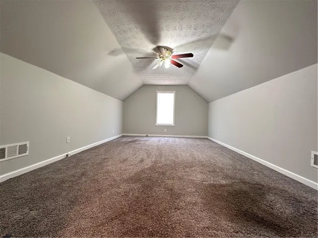 an empty room with a chandelier fan and windows