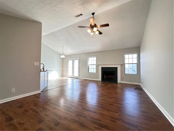 an empty room with wooden floor fireplace and windows