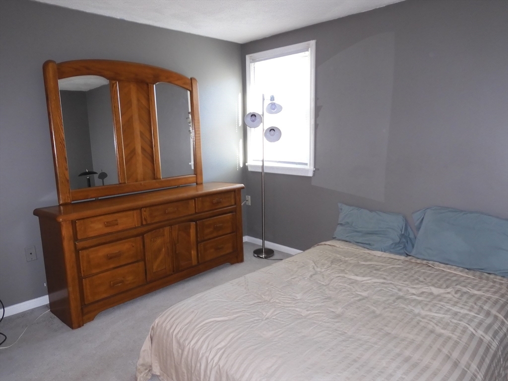 115 Merrimack Road, Unit 115 Methuen, MA 01844 - Photo 17 of 23 a bedroom with a bed and a mirror on dresser