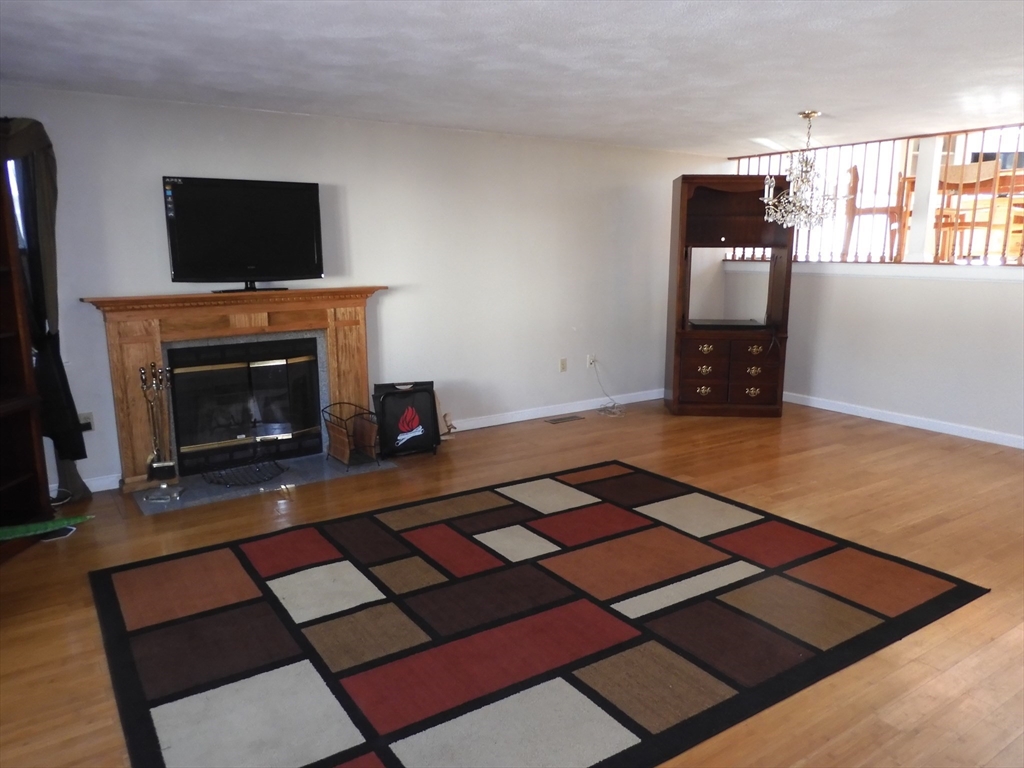 115 Merrimack Road, Unit 115 Methuen, MA 01844 - Photo 2 of 23 a living room with a fireplace and a flat screen tv