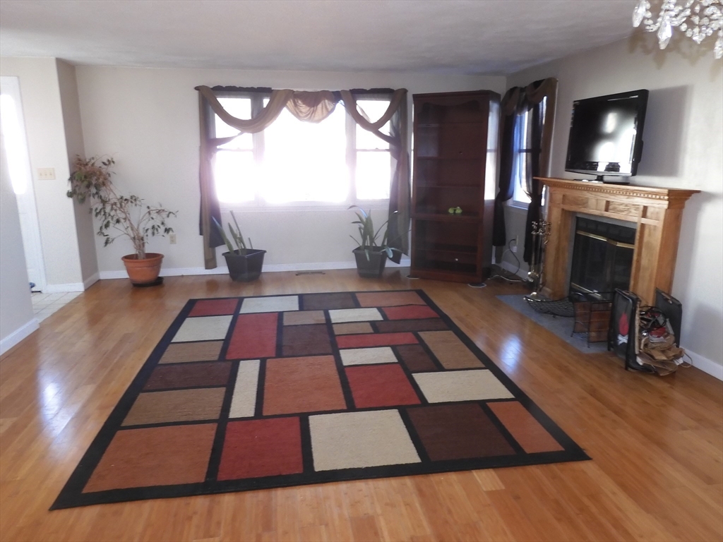 115 Merrimack Road, Unit 115 Methuen, MA 01844 - Photo 3 of 23 a picture of a living room with a rug floor and a fireplace