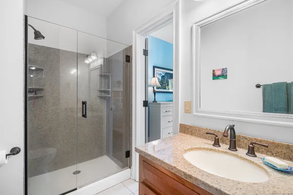 a bathroom with a granite countertop shower sink and mirror