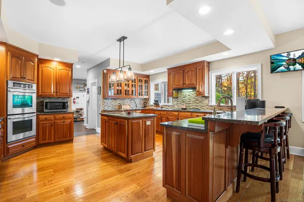 a kitchen with stainless steel appliances granite countertop wooden cabinets a stove a sink a dining table and chairs
