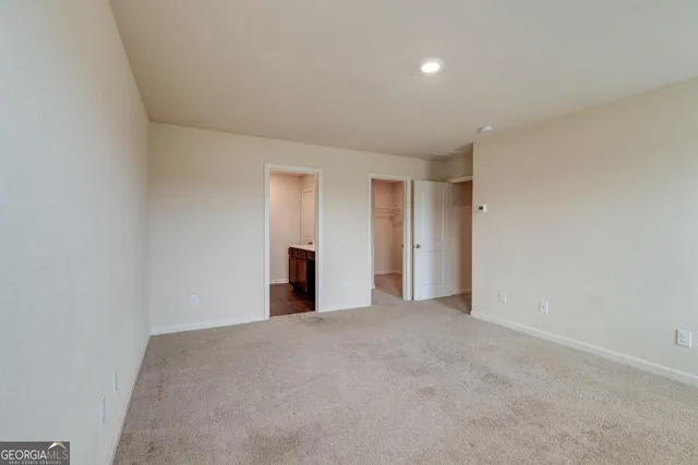 a view of an empty room with closet and bathroom