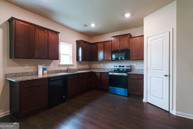 a kitchen with stainless steel appliances granite countertop wooden cabinets a stove a sink and a wooden floor