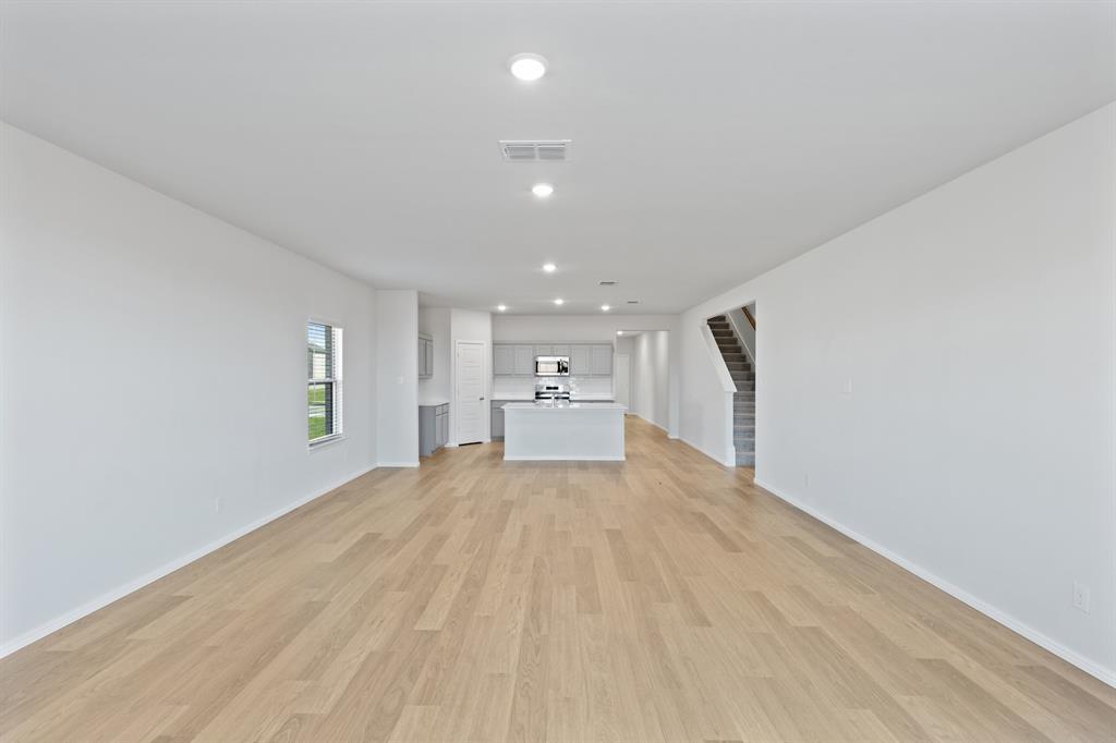 7636 Kingfisher Road Aubrey, TX 76227 - Photo 13 of 34 a view of a big room with wooden floor and windows