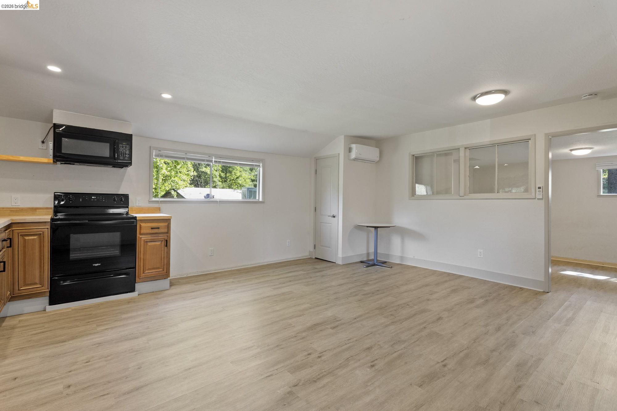 18363 Yosemite Road Tuolumne, CA 95379 - Photo 22 of 34 Open-concept living area featuring wood-finish flooring, recessed lighting, and a kitchen area with wood cabinetry, a black range, and an over-the-range microwave