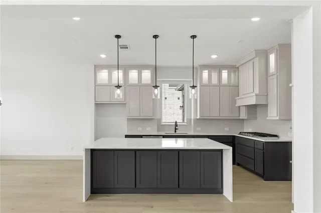 a kitchen with kitchen island granite countertop a sink a counter space appliances and cabinets