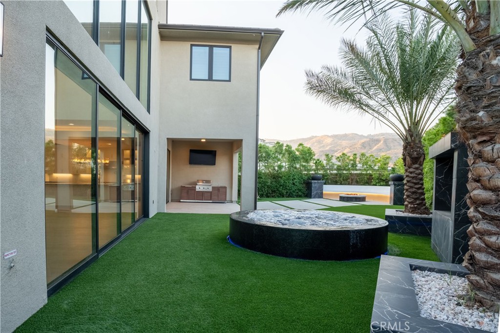 20043 Mersey Lane Porter Ranch, CA 91326 - Photo 67 of 68 a view of a patio with table and chairs potted plants and palm trees