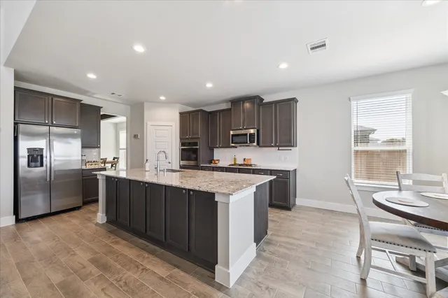 a kitchen with stainless steel appliances granite countertop a sink counter space cabinets and a large window