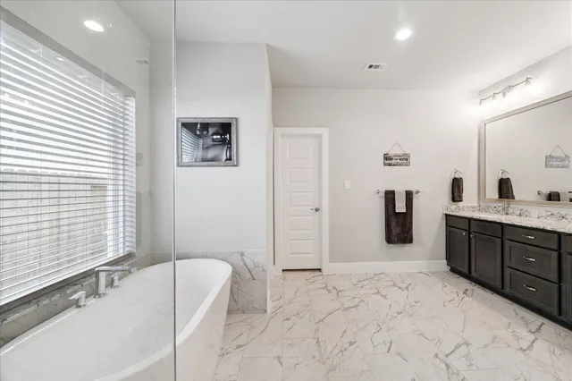 a spacious bathroom with a tub sink and mirror