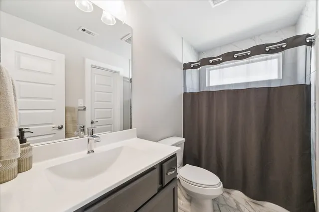 a bathroom with a sink a toilet a mirror and shower curtain