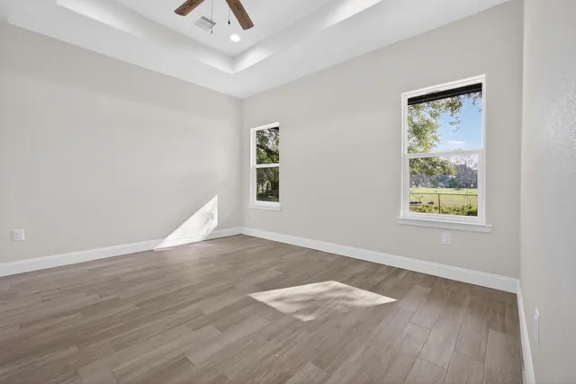 an empty room with wooden floor and windows